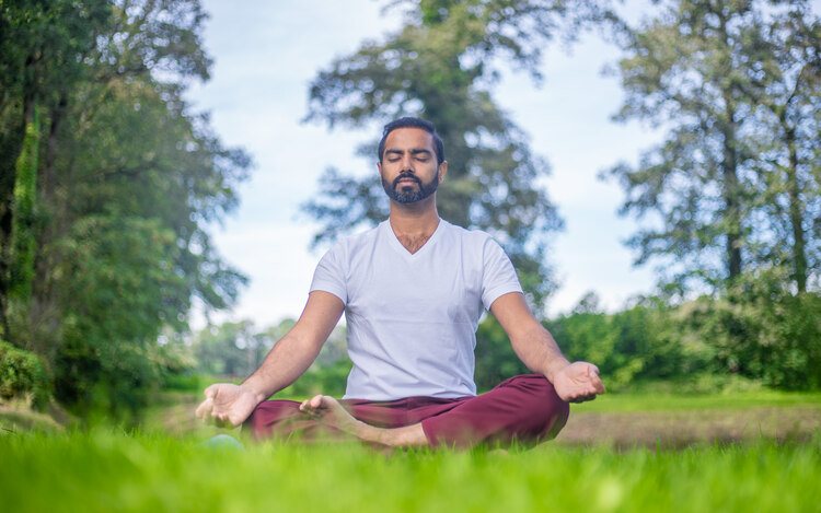 A yoga teacher sits in lotus pose outside in nature, practicing Kapalbhati Pranayama for metabolism increase A yoga teacher sits in lotus pose outside in nature, practicing Kapalbhati Pranayama for metabolism increase