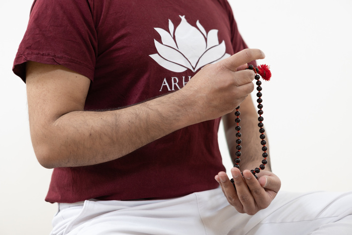 A yoga practitioner hold mala japa beads in his yoga studio at home
