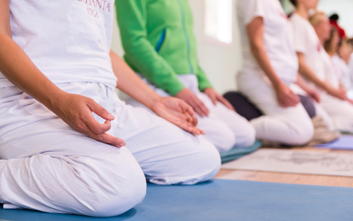 Yoga students sit on a yoga cushion during meditation