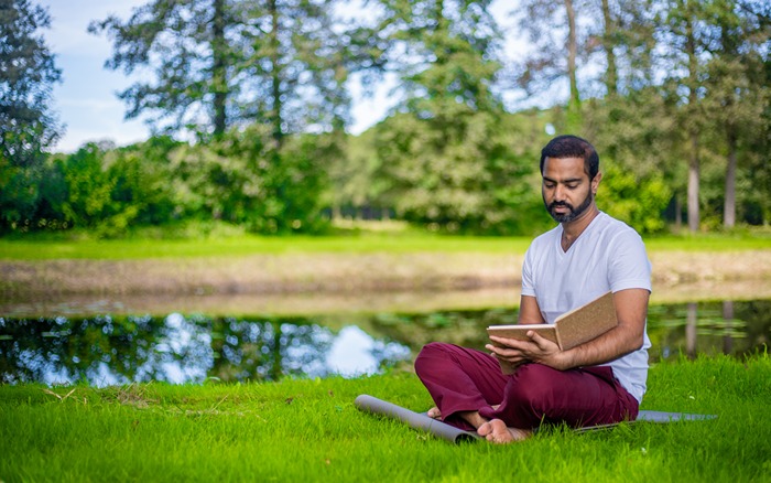 A yoga practitioner practices Svadhyaya (self study) outside A yoga practitioner practices Svadhyaya (self study) outside