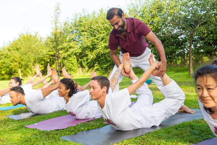 A yoga teacher adjusts a student in Bow Pose A yoga teacher adjusts a student in Bow Pose