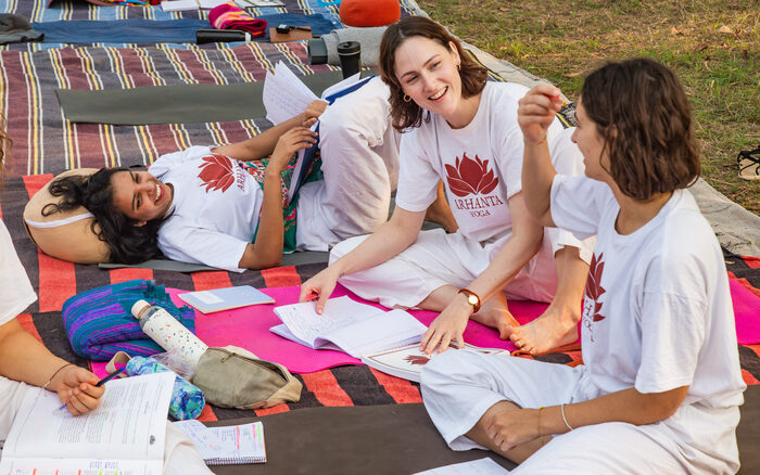 Aspiring yoga teachers sit outside reading yoga texts together