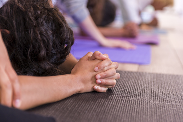 Yoga student’s hands resting on a yoga mat