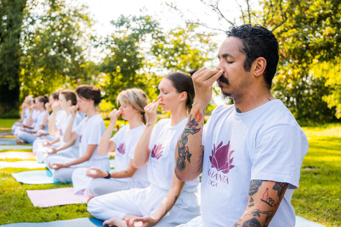 Class of yoga students practice nadi shodhana (alternative nostril breathing)