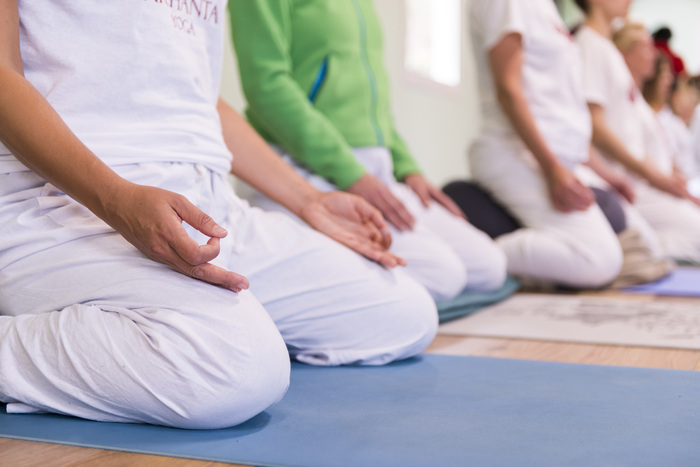 Yoga practitioners in seated meditation pose holding a mudra hand position Yoga practitioners in seated meditation pose holding a mudra hand position