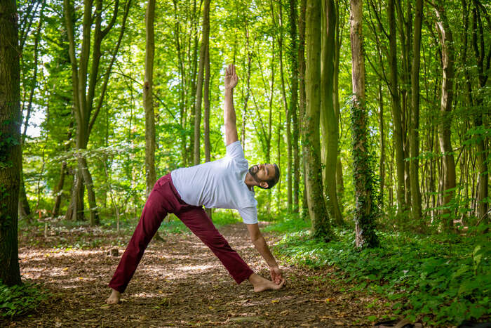 A yoga practitioner bends in a yoga pose outdoors in nature