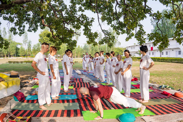 A yoga teacher instructs students in a yoga class outside A yoga teacher instructs students in a yoga class outside