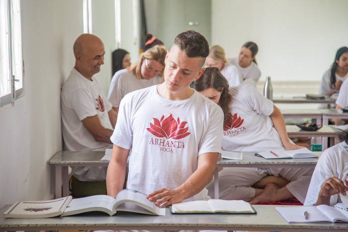 A young man reads a book in a yoga class A young man reads a book in a yoga class