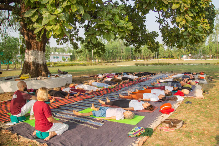 Yoga students lie in corpse pose on a yoga training course in India