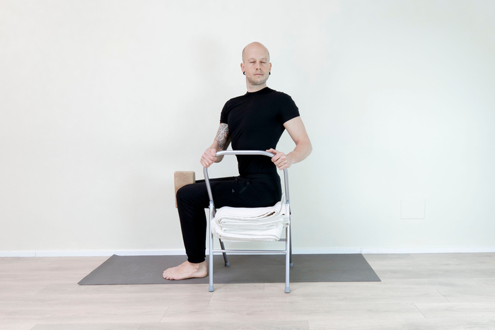 A man demonstrates chair yoga for men over 40