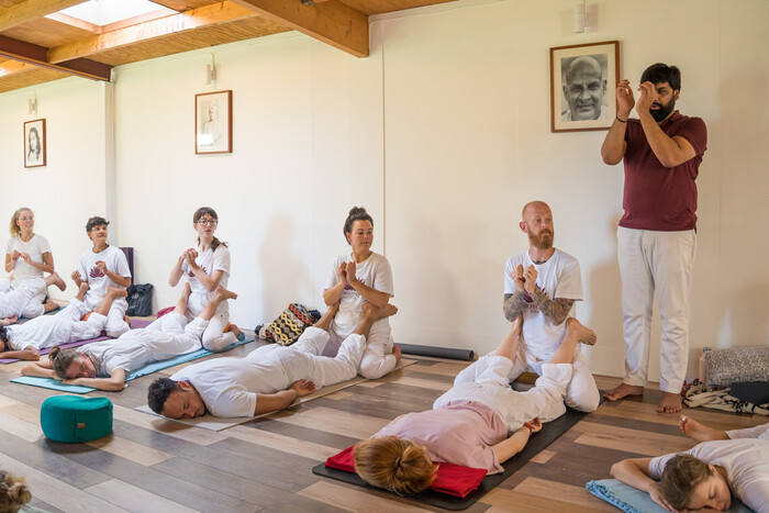 A yoga teacher instructs a small class on a yoga teacher training A yoga teacher instructs a small class on a yoga teacher training