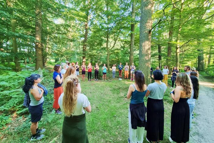 Group of yoga students standing in a circle surrounded by a lot of greeneries Group of yoga students standing in a circle surrounded by a lot of greeneries