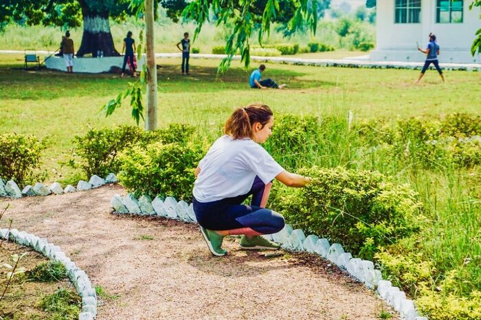 Students practicing Karma Yoga by helping with gardening tasks Students engaged in mindful gardening during their Karma yoga session