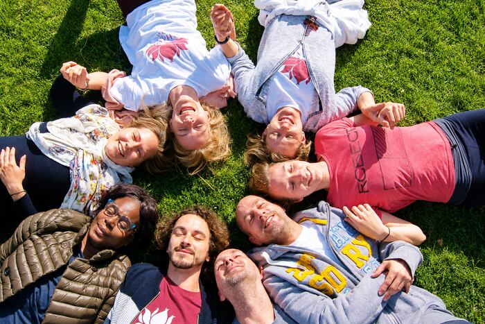 A group of YTT graduates lying in a circle, smiling, relaxing and building a supportive community
